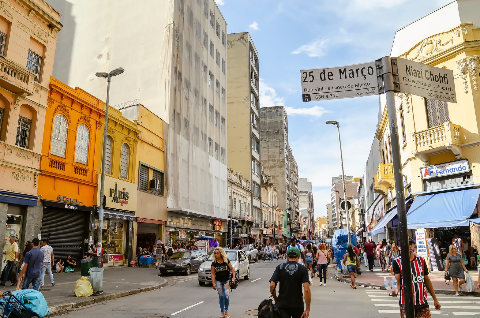 “Movimento na Rua 25 de Março, em São Paulo, com pedestres e comércio ativo; ConectCar facilita o estacionamento na região.