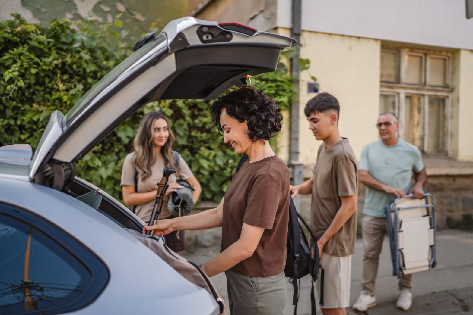 Pessoas organizando bagagens no porta-malas para viagem de carro, com mais praticidade nos pedágios usando a tag ConectCar.